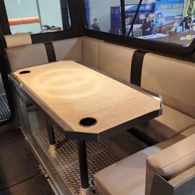 Boat interior with a table and beige cushioned seating around it.