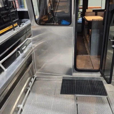 Metal boat interior with seating and door open, revealing cabin with lights and equipment.