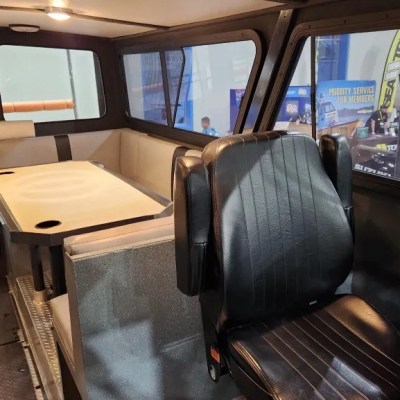 Interior of a metal cabin with a table, seating, and large windows.