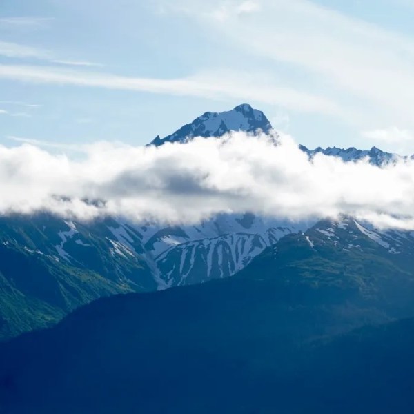 Snow-capped mountains with clouds and a bright sky.