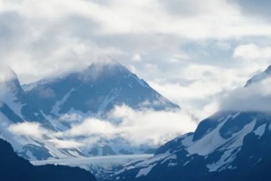 Scenic view of snow-capped mountains shrouded in clouds.