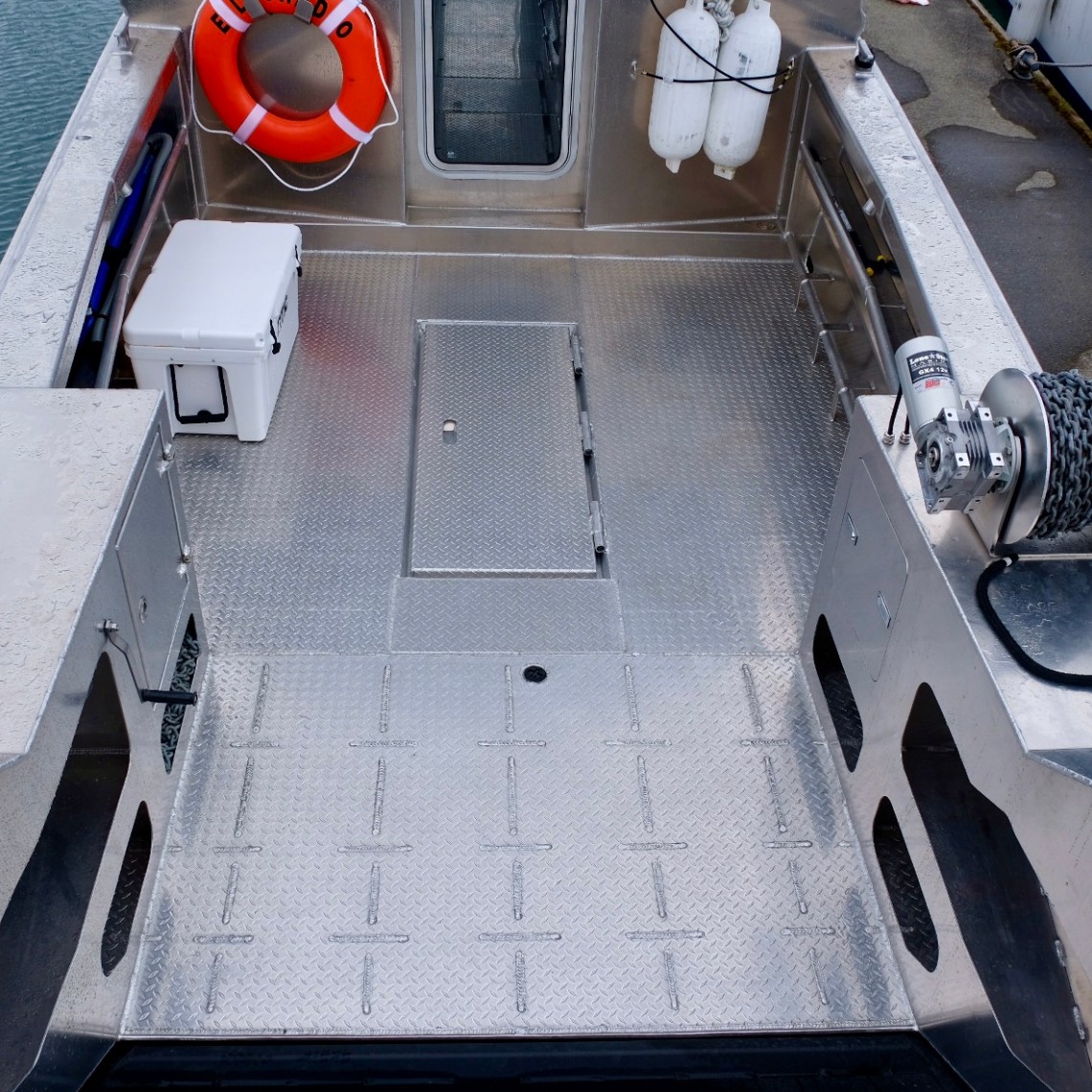 Metallic boat deck with life ring and equipment near dock.