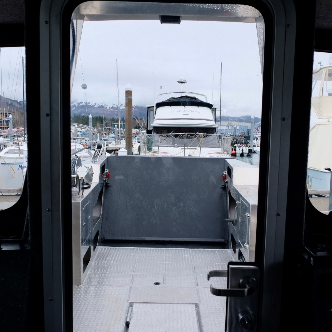 View from inside a boat looking out to a marina with multiple docked boats.