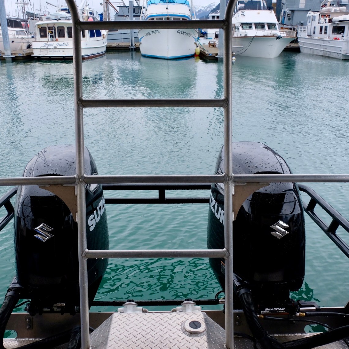 View from boat stern showing two outboard engines at marina.