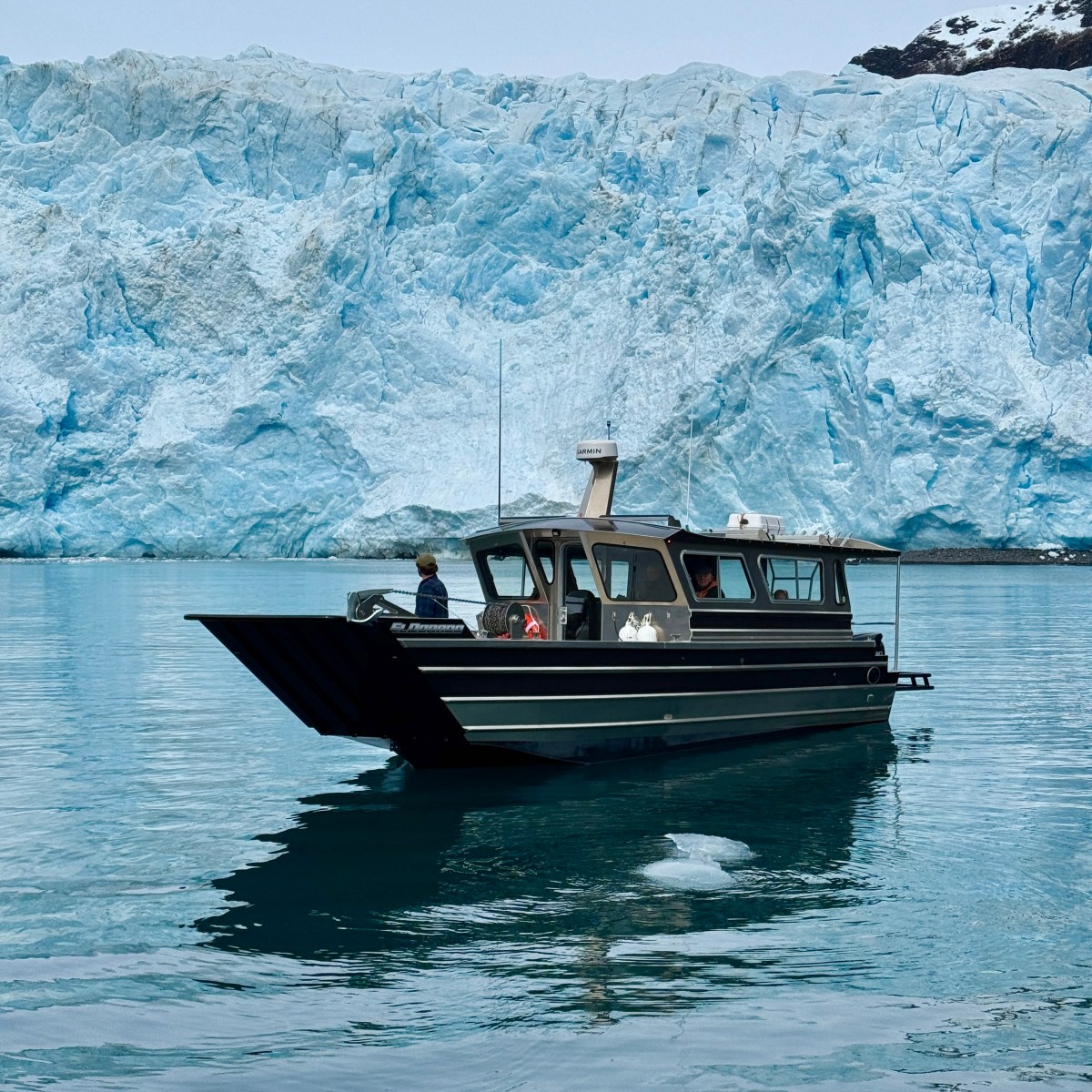 Boat on water with a large glacier in the background.